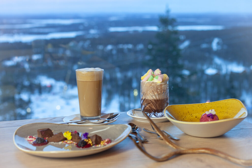 Ravintola Panoraman jälkiruoka-annokset ja kahvit pöydällä, takana upea Levin tunturimaisema.